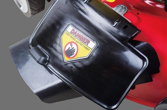 2026/06/1002286584.jpg - pricemagicgh.com Close-up of a black motor cover with a yellow danger sticker that reads 'DANGER KEEP HANDS AND FEET AWAY' on red equipment, implying a hazardous power tool.