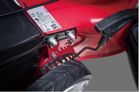 2026/06/1002286586.jpg - pricemagicgh.com Close-up of a red motorcycle's rear area, showing the tire, foot peg, and a safety label on the frame.