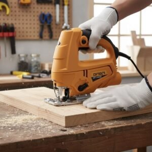 Person wearing gloves guiding an orange electric jigsaw to cut a wooden board on a workbench in a workshop.