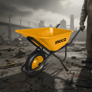 Yellow Ingco wheelbarrow on cracked ground at a rubble-filled construction site with a worker holding the handles in view.