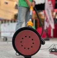 2026/06/1002860491.jpg - pricemagicgh.com Red circular cable reel on the ground at an outdoor event, with a person in a green shirt and jeans visible in the background.