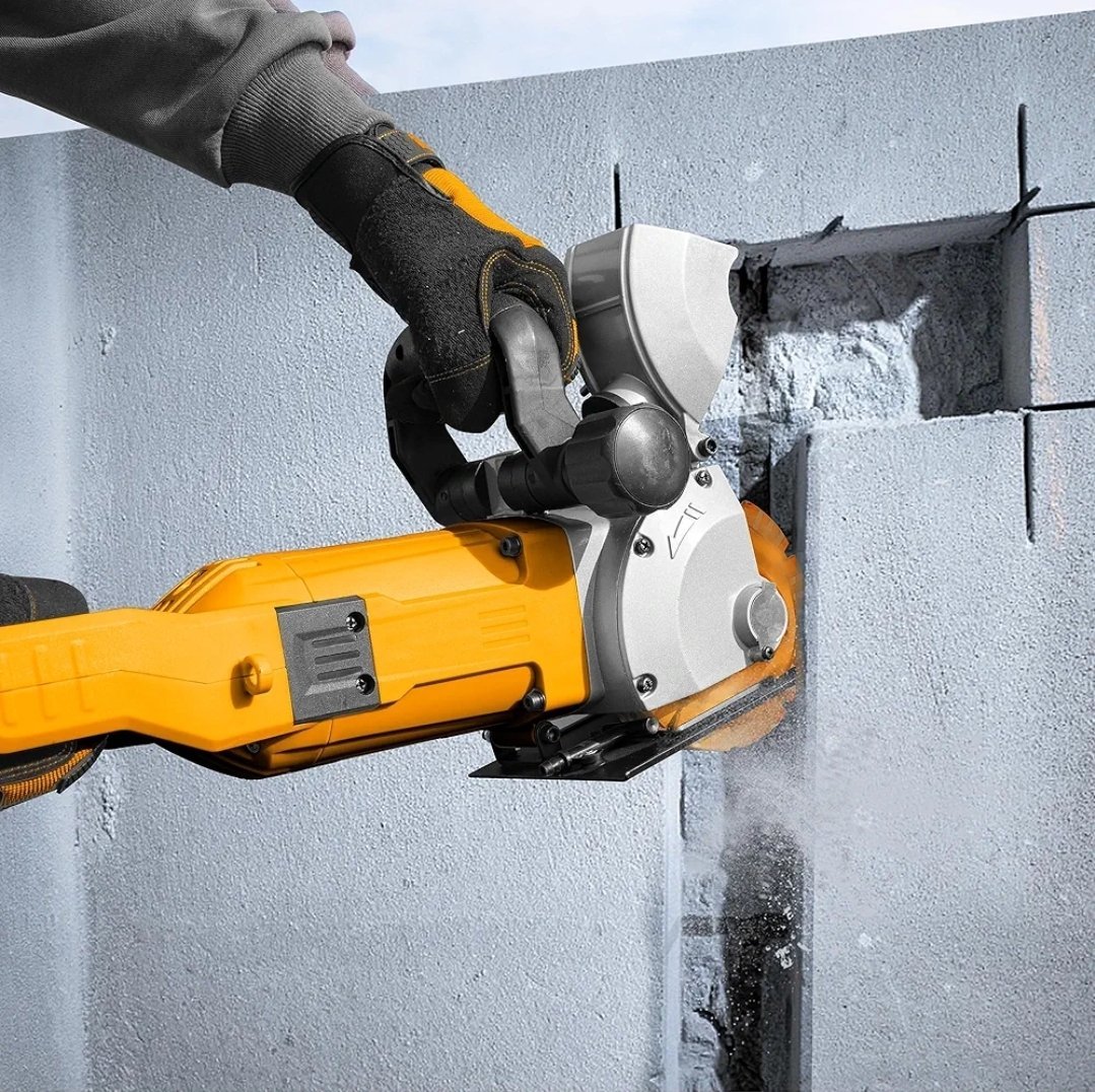 2026/06/1002864448.jpg - pricemagicgh.com Worker wearing a glove operates a yellow handheld masonry cutter, slicing through concrete blocks with dust spray