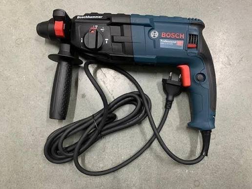 2026101003441206jpg pricemagicghcom Bosch corded hammer drill with side handle and red trigger lying on a concrete surface